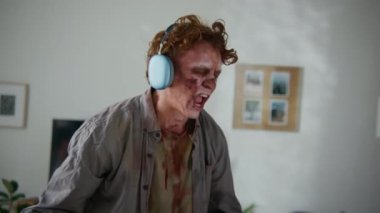 Beyaz gözlü, kan lekeli günlük kıyafetleri olan, kablosuz kulaklık takan, müzik eşliğinde şarkı söyleyen, dans eden, titreyen, hava gitarı çalan neşeli erkek zombilerin orta boy yakın çekim el çekimi.