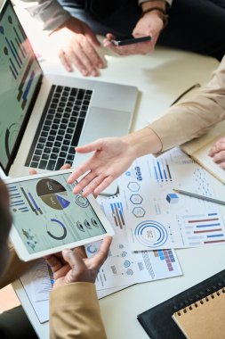 Erkek meslektaşı tarafından tutulan tablet ekranındaki mali belgeye işaret eden tanınmayan iş kadınının yüksek açısı