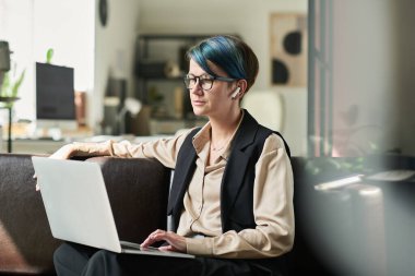 Dizlerinin üzerine çökmüş, deri koltukta oturan ve internetten bilgi toplayan genç, ciddi bir kadın analist.