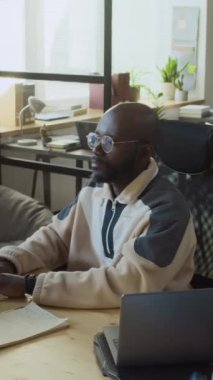 Bilgisayarda yeni yazılımı test eden kendinden geçmiş genç siyahi erkek geliştiricinin orta dikey görüntüsü başarılı sonuçlar alıyor, neşeyle tezahürat yapıyor ve yumruklarını sallıyor.