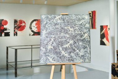 Sanat galerisinin duvarlarında asılı modern sanat eserleri arasında sehpada sergilenen yeni ve soyut bir tablo