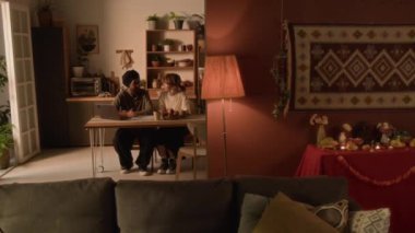 Mutfak masasında dizüstü bilgisayarla oturup sohbet eden, aile sorunlarını tartışan ya da rahat bir evde yeni planlar yapan evli çiftlerin tam bir karesi.