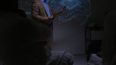 Sağlık uzmanları karanlık seminer odasında dinleyiciler arasında oturuyor, beyin implantı teknolojisi ve alkışlayan hoparlör sunumunu dinliyorlar.