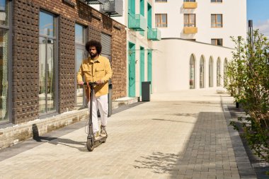 African American man riding electric scooter on a modern, sunlit urban street with various building exteriors visible in background clipart