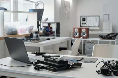 Gelişmiş teknoloji ve aletlerin bulunduğu modern ofis. Yüksek teknolojili ve organize bir çalışma alanına katkıda bulunan çeşitli cihazlar ve elektronik ekipmanlar masalarda görünür.
