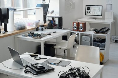 Çeşitli elektronik aletlerin ve cihazların titizlikle beyaz masalara yerleştirildiği modern çalışma alanı, teknolojik yenilik ve geliştirme için bir atmosfer oluşturmaktadır.