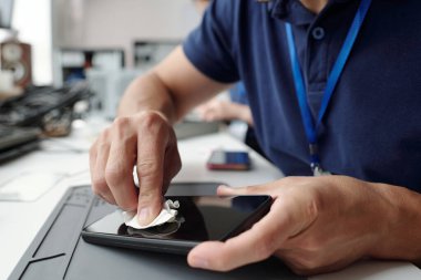 Eller profesyonel ofis ortamında kumaşla tablet ekranı temizliyor. Alet ve teknoloji kullanımı günlük çalışma rutininde belirgindir.