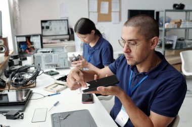 Modern ofis ortamında devre kartı montajında çalışan mühendisler elektronik üretim sürecinde takım çalışması ve teknik becerileri sergiliyor