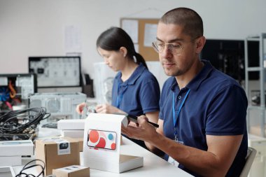 Modern ofis ortamında iş birliği yapan insanlar. Elektronik aygıtlar ve bileşenlerle çalışmak, projenin tamamlanmasını sağlamak