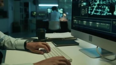 Odaklanmış, omuz bantlı, operasyon merkezinde bilgisayar üzerinde çalışan, potansiyel tehditler için uydu gözetleme görüntülerini analiz eden, üniformalı bir askerin yan görüntüsü.