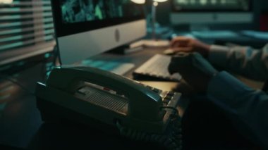 Gece vardiyasında bilgisayarın başında oturan tanınmayan bir gözetleme ajanının elleri kapalı. Uydu görüntülerindeki şüpheliyi tespit ediyor. Sabit telefondan amirine bildirmek için arıyor.