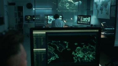 Erkek ordu subayının bilgisayarda uydu görüntülerini izlediği ve operasyon merkezinde gece vardiyasında çalışırken keşif yaptığı arka omuz üstü çekim.