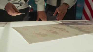 Komuta merkezinde durmuş, haritalar üzerinde tartışan tanınmayan erkek ve kadın ordu subaylarının elleri kapalı.