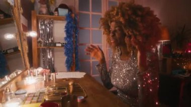 70 'li yaşlarda, parlak gümüş elbiseler giyen, sesini ısıtan ve kendini beğenmişlerin soyunma odasındaki aynanın önünde gösteriş yapan siyahi kadın şarkıcı.