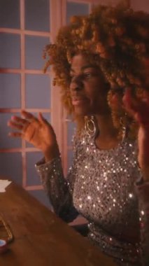 70 'lerin parlak gümüş elbiseli, kabarık saçlı genç siyahi kadın şarkıcısının dikey pozu. Sesini ısıtıyor ve kendini beğenmiş aynanın önünde soyunma odasında gösteriş yapıyor.