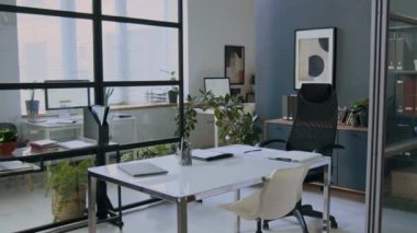 Minimalist tasarımı olan modern ofis, beyaz masa, ergonomik sandalyeler, bitkiler ve cam duvar