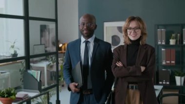 Afrika kökenli Amerikalı iş adamı ve Kafkas kadın meslektaşının resmi kıyafetleri içinde kamera önünde poz verirken ve gülümserken portresi