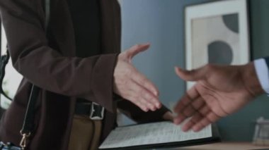 Ofisteki toplantıda tanınmayan bir kadının belgelerini tutması ve mali danışmanla el sıkışması.