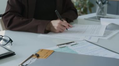 İş kredisi anlaşmasını imzalayan kadının yakın plan fotoğrafı, sonra da ofiste yapılan toplantıda mali danışmana incelenmesi için verirken.