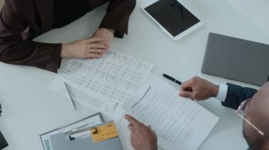 Siyahi finansal danışmanın beyaz kadın müşteriden imzalı iş kredisi anlaşması aldığını, ona belgeler ve kredi kartı verdiğini, sonra da ofis masasında el sıkışmayla anlaşmayı mühürlediğini gösteriyor.