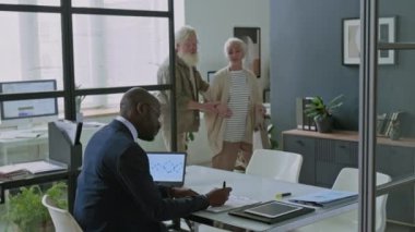 Ofise gelen yaşlı beyaz çift danışmadan önce masaya oturuyor ve Afrikalı Amerikalı mali danışmanı selamlıyorlar.