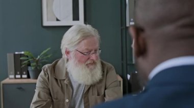 Siyahi finansal danışman ile görüşen ve belgeyi görüşen Kafkasyalı yaşlı çiftin omuz hizasında