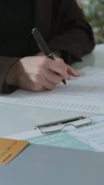 İş kredisi anlaşmasını imzalayan ve banka memuruna teslim eden tanınmayan bir kadının elleri dikey yakın plan.