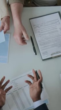 Ofis toplantısından sonra tanınmayan mali danışmanın üst düzey müşteriyle el sıkışmasının dikey aşağı çekimi.