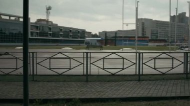 Beyaz tenli, engelli, kapüşonlu, kapüşonlu bir sporcunun, bulutlu bir yaz günü antrenmana giderken boş bir stadyumda koşu parkurunda yürüdüğü tam kamyon fotoğrafı.