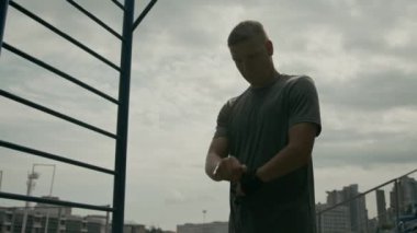 Kafkas engelli genç sporcunun antrenmana hazırlanırken, barfiks çekerken ve barfiks çekerken orta açılı resmi.