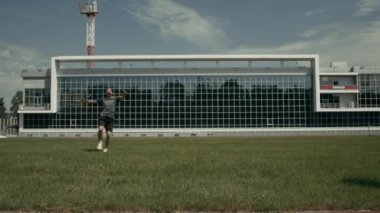 Engelli profesyonel para-sporcunun açık hava stadyum tesisindeki yeşil sahada koşarken, güç ve hızıyla cirit atarken, yarışma için antrenman yaparken geniş açılı yavaş çekimi.
