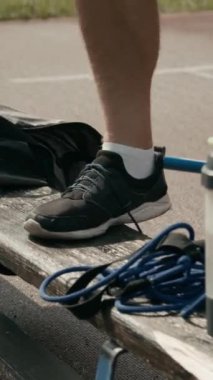 Yazın stadyumda antrenman yapmadan önce spor ayakkabılarına bağcıklarını bağlayan isimsiz erkek para atletinin elleri dikey olarak birbirine yakın.