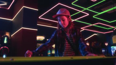Beyzbol şapkalı, orta boy beyaz bir çocuğun atari salonunda arkadaşlarıyla hokey oynarken, gol atarken, tezahürat yaparken ve keyifle yumruk atarken.