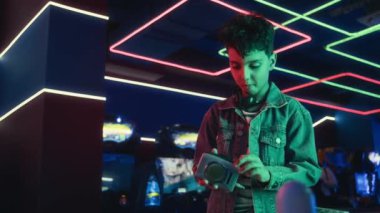 Kot ceketli, çift ırklı bir gencin retro kaset çalarına bant yerleştirip en sevdiği şarkıyı dinlerken, oyun salonunda arkadaşlarıyla takılırken orta boy fotoğrafı.