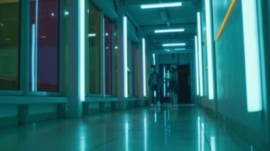 İki genç çocuğun oyun salonuna giderken neon koridorda yürürken, hararetli bir konuşma ya da tartışma yaparken,