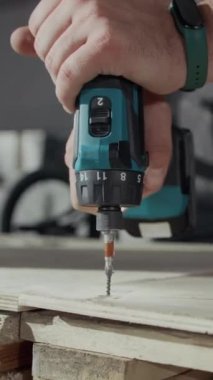 Tahta paleti delmek için sürgülü matkap kullanan, BMX sürmek için tahta rampa parçaları birleştiren isimsiz bir adamın dikey yakın çekimi.