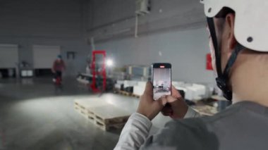 Omzunda akıllı telefon tutan ve BMX bisikletli arkadaşının video kaydını yapan, hangarda tavşan zıplaması yapan, telefon ekranının odak noktası, uzay kopyalama yapan bir adamın fotoğrafı.