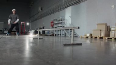 Korumalı kask takan, depoda paten kayan, çelik parmaklıklarda atlayıp kayan, ekstrem sporlar yapan genç bir adamın düşük derece yavaş çekimi.