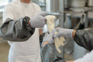 Profesyonel mutfakta hassasiyetle mozzarella peyniri esneten şeflerin elleri, koruyucu eldivenler ve temiz çevre ile zanaatkar peynir üretim sürecini gözler önüne seriyor.