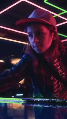 Arcade 'de arkadaşlarıyla hava hokeyi oynarken hafta sonları dinlenen, şevkli, şevkli, beyaz tişörtlü ve şapkalı bir çocuğun orta boy dikey pozu.