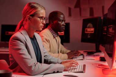 Bilgisayar ekranı önünde oturup yazı yazarken teknik sorunları çözen genç, ciddi bir bayan güvenlik görevlisi.