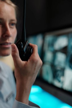 Elinde telsiz olan genç güvenlik görevlisinin gözlem odasındaki otel resepsiyonunda kaza olduğunu bildirmesine odaklan.