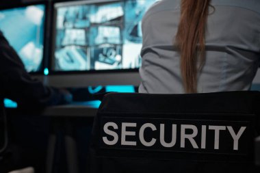 İş yerinde oturan uzun sarı saçlı genç bayan gardiyanla birlikte siyah üniformanın arkasındaki kelime güvenliği.