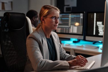 Tuş takımında yazan ve erkek iş arkadaşına karşı bilgisayar ekranına bakan ciddi bir kadın IT destek yöneticisiName