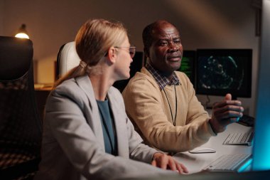 Bilgisayar ekranında verileri tartışırken sarışın genç meslektaşının yanında oturan kendinden emin bir erkek programcı.