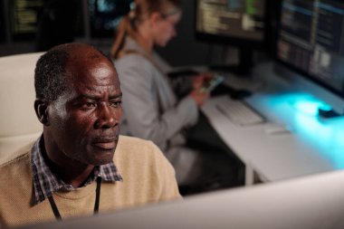 Çevrimiçi veri çözerken veya yeni yazılım geliştirirken masaüstü bilgisayar ekranına bakan ciddi deneyimli bilişim mühendisi