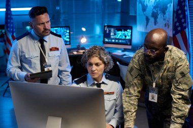 Üniformalı üç kültürler arası ordu mensubu bilgisayar ekranına bakıyor ve çevrimiçi bilgileri tartışıyorlar.