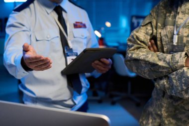 Çevrimiçi verileri meslektaşıma açıklarken üniformalı yetişkin bir erkek askerin masaüstü bilgisayar ekranını göstermesi.