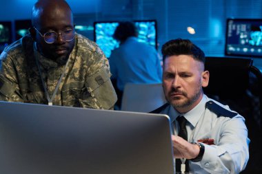 Çevrimiçi bilgi sunumu sırasında masaüstü bilgisayar ekranına bakan ve işaret eden ciddi yetişkin erkek operatör