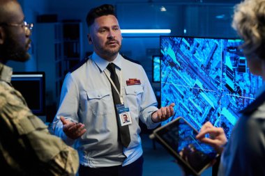 Etkileşimli ekranda ordunun yerini tartışırken iki kültürler arası meslektaşın önünde duran kendinden emin bir adam.